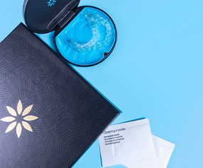 Bird’s eye view of Invisalign in case next to folder and packets of cleaning crystals