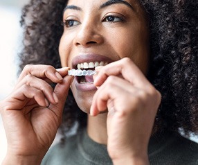 Woman with curly hair removing Invisalign from her upper arch