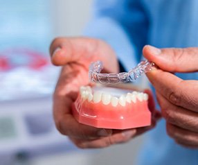Dentist placing Invisalign over sample teeth