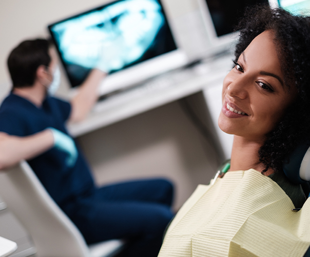 Woman in dental chair smiling at dentist