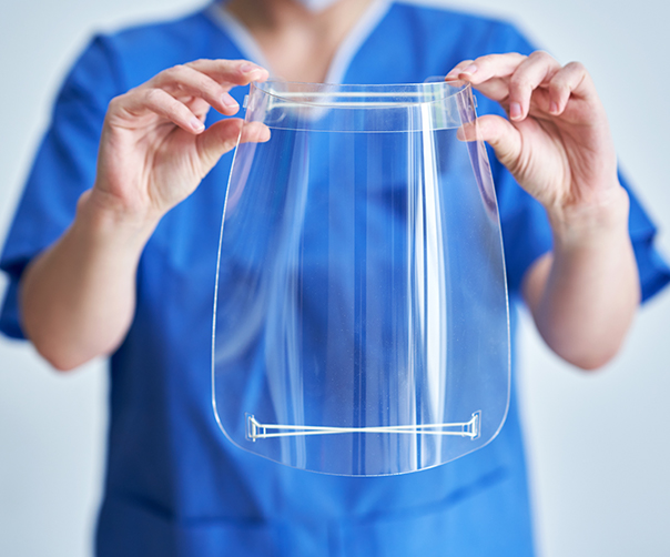 Dental team member holding clear facial shield