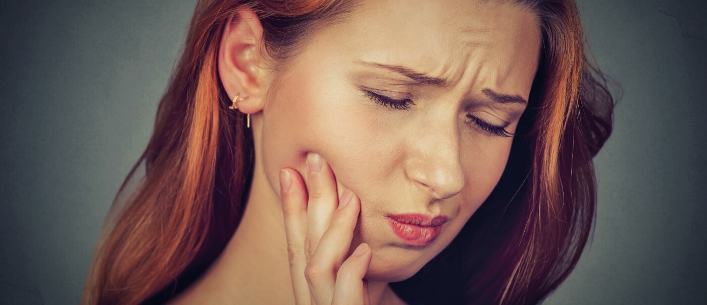 Woman in need of emergency dentistry holding jaw