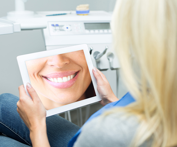 Woman looking at virtual smile design on tablet computer