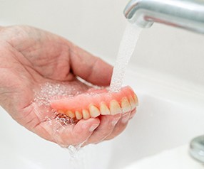 Person rinsing their upper denture