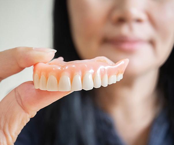 A woman holding a denture