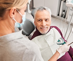 A dentist presenting an elderly man with a dental impression