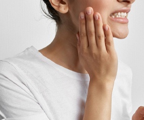 woman holding cheek from the cost of emergency dentistry in Tyler