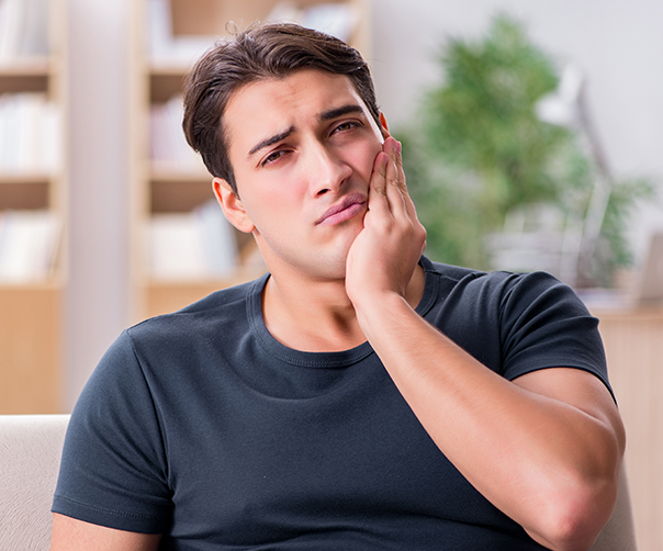 Man in need of tooth extraction holding jaw in pain