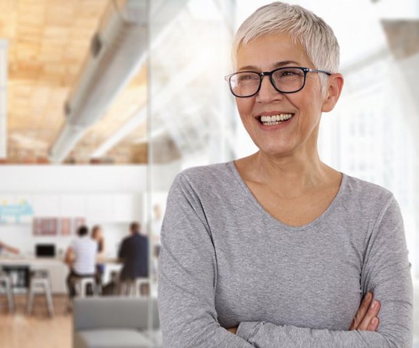 woman in a gray shirt crossing her arms and smiling 