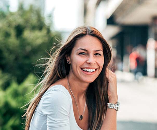 Woman with dental implants in Tyler, TX outside and smiling