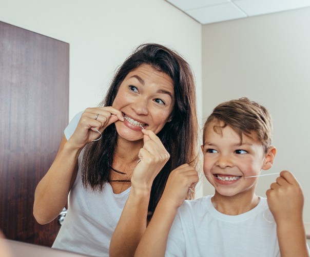 Mother and son preventing dental emergencies in Tyler by flossing