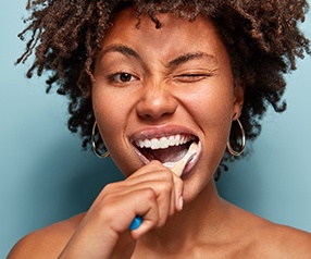 Woman brushing her teeth to prevent dental emergencies in Tyler