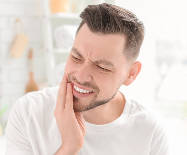 Man holding jaw in pain before root canal therapy