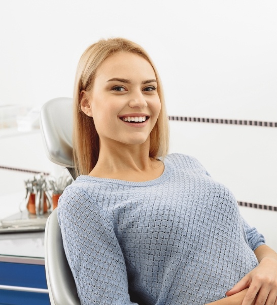 Woman in dental chair smiling after preventive dentistry visit