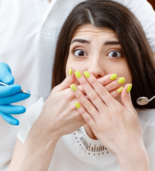 Woman in need of sedation dentistry covering her mouth