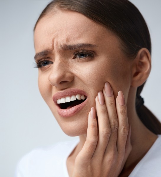 Woman in need of emergency dentistry holding jaw