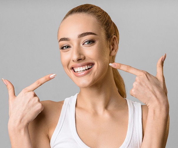 Woman pointing to her smile with veneers in Tyler