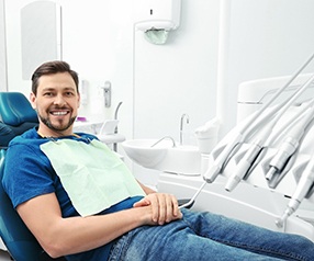 Man in blue shirt smiling while sitting in the dental chair