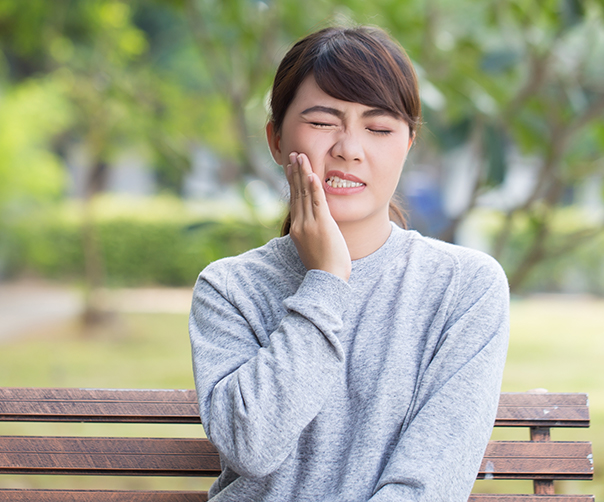 Woman in need of tooth extraction holding jaw in pain