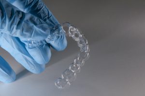 Gloved hand holding Invisalign aligner