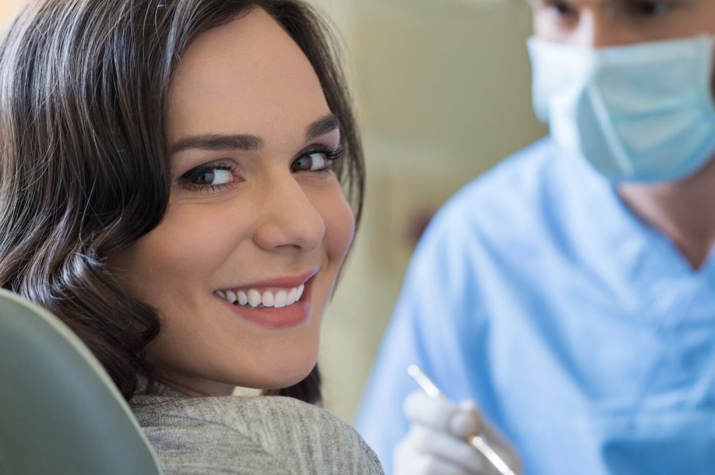 person with dental implants smiling at dentist