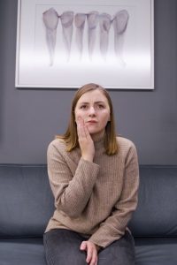 Woman with hand on face at dentist