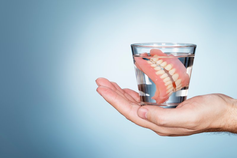 dentures being dropped in a glass