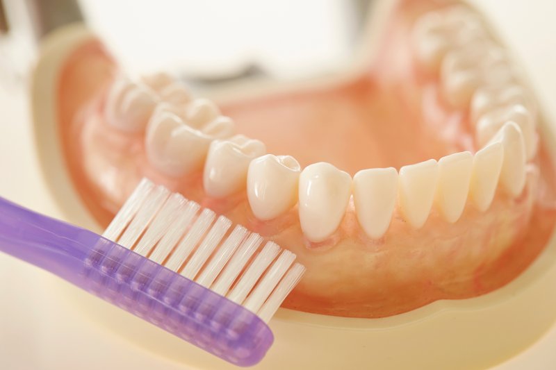 Purple toothbrush cleaning bottom set of dentures