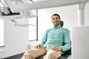 Male dental patient sitting in chair and smiling